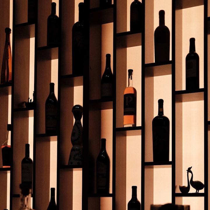 Regalwand mit Silhouetten von verschiedenen Flaschen vor beleuchtetem Hintergrund.